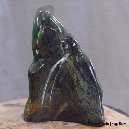 A deep green and bronze soapstone sculpture combining smoothness and natural roughness of the stone.