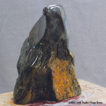 A deep green and bronze soapstone sculpture combining smoothness and natural roughness of the stone.