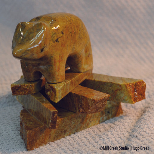 Golden and copper Brazilian Soapstone shot through with black veins, this mountain bear rests on his rocky base.