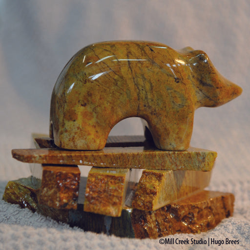 Golden and copper Brazilian Soapstone shot through with black veins, this mountain bear rests on his rocky base.