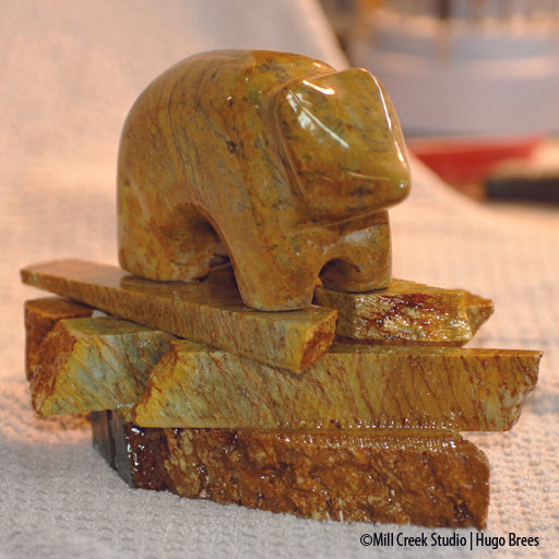 Golden and copper Brazilian Soapstone shot through with black veins, this mountain bear rests on his rocky base.