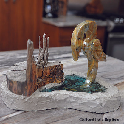 This mixed media soapstone piece depicts a bird fishing in it's environment of tree, water, and mollusks.
