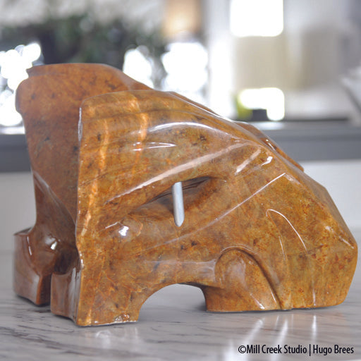 A shock of copper hued Brazilian Soapstone, the sculpture depicts the need for freedom from its captured form.