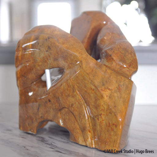 A shock of copper hued Brazilian Soapstone, the sculpture depicts the need for freedom from its captured form.