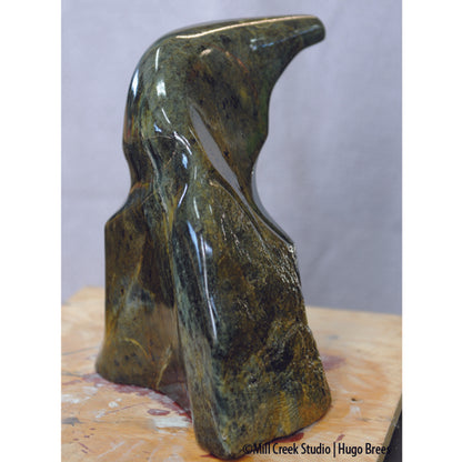 A deep green and bronze soapstone sculpture combining smoothness and natural roughness of the stone.